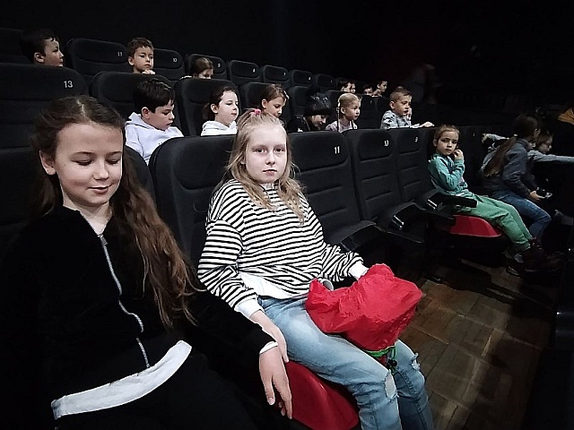 Uczniowie siedzący w fotelach na sali kinowej.